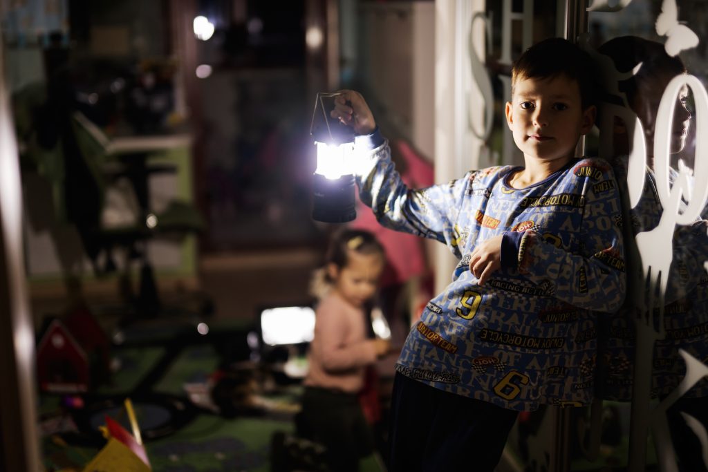 Boy at home during a blackout using a flashlight lantern